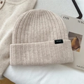 Close-up of 100% wool beige ribbed knit beanie with high-quality texture and brand tag - Beige