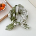 Green tie-dye cotton scarf tied in a bow on a white surface with lifestyle props - Ink Green