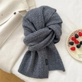 Detailansicht eines grauen Strickschals aus Wolle mit Zopfmuster und Wollsiegel - Weizengrau