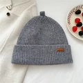 Detail of dark gray ribbed knit beanie with leather label and unique top loop detail - Gray