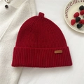 Close-up of deep red ribbed knit beanie with leather logo tag and winter decor - 28*25cm / Red