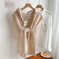 Close-up of beige chunky knit hooded shawl with brand tag on a wooden hanger - Beige