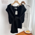 Detailed knit texture and authentic brand tag on a black fashionable knitted shawl cape - Black