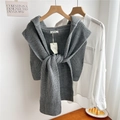 Detail of dark grey rib-knitted vest with knot design on a wooden hanger setup - Gray