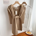 Detail showing thick camel knitted shawl with elegant long straps in a warm indoor setting - Camel