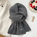 Detail of dark grey knit scarf with vertical texture and decorative silver metal tag - Gray