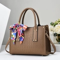 Detail of brown crocodile embossed leather handbag with silk scarf and gold studs - Khaki