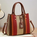 Detail of colorful striped canvas handbag with brown leather handles and rivet accents - Red