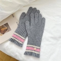 Close-up of gray ribbed knit gloves with pink striped cuffs and a decorative shell button - One Size / Gray