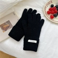 Close-up of 100% wool knitted gloves featuring elegant wavy cuffs and a minimal white label - Black