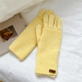 Close-up of bright yellow knitted gloves featuring a textured weave and leather tag - Bright Yellow