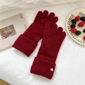 Detailed shot of dark red knit gloves featuring a heart metal tag on soft texture - One Size / Burgundy
