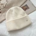 Detailed texture of off-white ribbed knit beanie with silver metallic bowlow logo - One Size / Cream