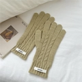 Detalle de guantes de punto trenzado beige que muestra texturas y etiquetas en la muñeca - Amarillo
