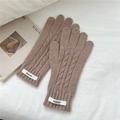 Detalle de guantes de punto trenzado café con textura de lana y etiqueta de marca tejida - café