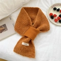 Caramel knit cross scarf with brand label on a cozy white bed background - Orange