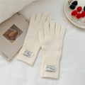 Detalle de guantes de punto blanco crema con puños acanalados y etiqueta decorativa - Talla única / crema