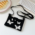 Detail of black knitted crossbody bag with white butterfly pattern on a white desk - 20cmx12cm / Black