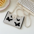 Close-up of knit crossbody bag with butterfly patterns and silver magnetic clasp - 20cmx12cm / White