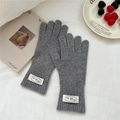 Detalle de guantes de punto gris oscuro con puños acanalados y una etiqueta blanca - Talla única / Gris Medio