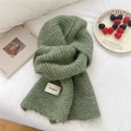 Soft sage green knitted scarf with fuzzy texture and woven brand tag on white bedding - Striped Green