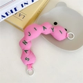 Close-up of pink puffy bag handle with green letter embroidery and white ring clips - Pink