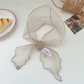 Detalle de bufanda de organza beige con bordes festoneados y cinta decorativa con texto - 15*115cm / Caqui