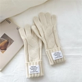 Detalle macro de guantes de punto de ochos beige con etiqueta de moda en el puño - crema