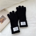 Detalle de guantes de punto negros con patrones de trenzas y una etiqueta tejida - Negro