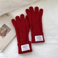 Primer plano de guantes de punto rojo con diseño trenzado y detalle de etiqueta - Rojo