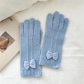 Gants en tricot bleu clair avec détail de nœud posés sur un tissu blanc doux - Taille unique / Bleu
