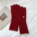 Close-up of red wool knit gloves with ribbed cuffs and decorative gold metal badge - One Size / Red