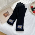 Detail of black knitted gloves featuring a ribbed wrist cuff and decorative bear patch - Full Finger / Black