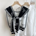 Dettaglio della mantella in maglia nera con motivo a fiocco bianco e bordo a contrasto - Nero (Linea Fine Fiocco)