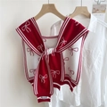 Dettaglio dello scialle in maglia con fiocchi rossi e targhetta del marchio sul bordo - Rosso (Linea Fine Fiocco)