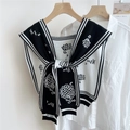Detail of floral knit shawl wrap with daisy patterns and tie front over a white shirt - Black (Sunflower)