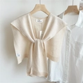 Dettaglio di uno scialle in maglia color crema con fiocco su gruccia in legno con camicia - 44*100cm / Beige con trama a fiocco