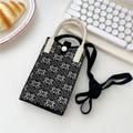 Detail der gestrickten Handytasche mit Schneeflockenmuster und Druckknopf auf Schreibtisch - Schneeflocke Diamant Schwarz