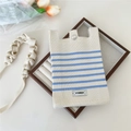 Close-up of a knitted striped mini crossbody bag with a metal button and woven strap - Blue Striped