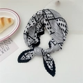 Pleated square scarf with black and white polka dots tied in a bow on a table - Beige Border Mixed Dots