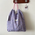 Detail of purple floral tote bag with drawstring texture and woven pink handle - Floral Purple