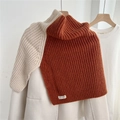 Détail d'un col en maille côtelée épaisse en caramel et crème sur un cintre en bois - Orange & Beige