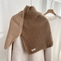 Gros plan du col roulé en maille côtelée marron porté sur un manteau beige élégant - Camel & Beige