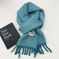 Detail of teal chevron knit scarf featuring fringe ends and a branded woven label - Blue