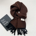 Close-up of brown and black chevron knit scarf with fringe and white brand label - Brown