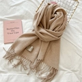 Detalle de bufanda de lana camel suave con flecos elegantes y etiqueta de cuidado - Beige