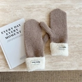 Close-up of thick knit mittens with fleece cuffs and brand label on marble surface - Brown
