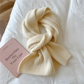 Detail of cream cable knit scarf with woven label on a cozy textured background - Creamy White