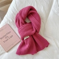 Detailed macro view of deep pink knitted scarf with ribbed texture and white brand label - Magenta