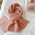 Detail of pink knitted rib scarf with woven label on a cozy white aesthetic background - Pink